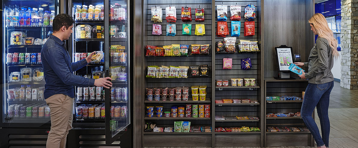 Employees using a self-checkout micro market with cooler and snacks in a modern workplace